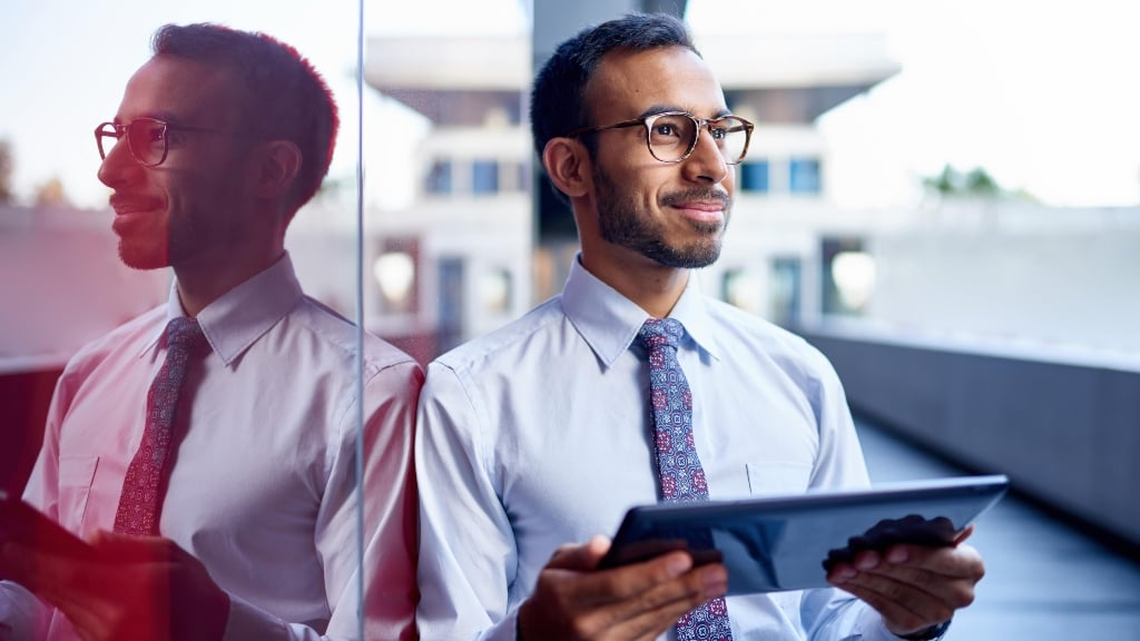 iStock-681904114-min (1Man With iPad and Looking With Building in the Background 